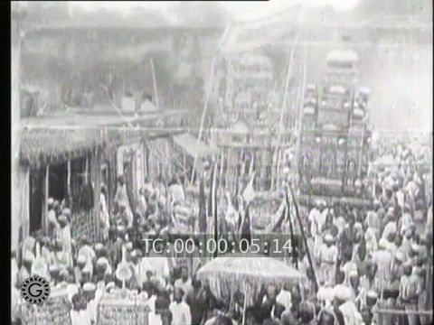 INDES. A TRAVERS LES RUES INONDEES PAR SUITE D'UNE PLUIE TORRENTIELLE SE DEROULE UNE CURIEUSE PROCESSION DE MUSULMANS FANATIQUES (India. Across the Streets Flooded by a Torrential Rain, a Curious Procession of Fanatic Muslims takes place)